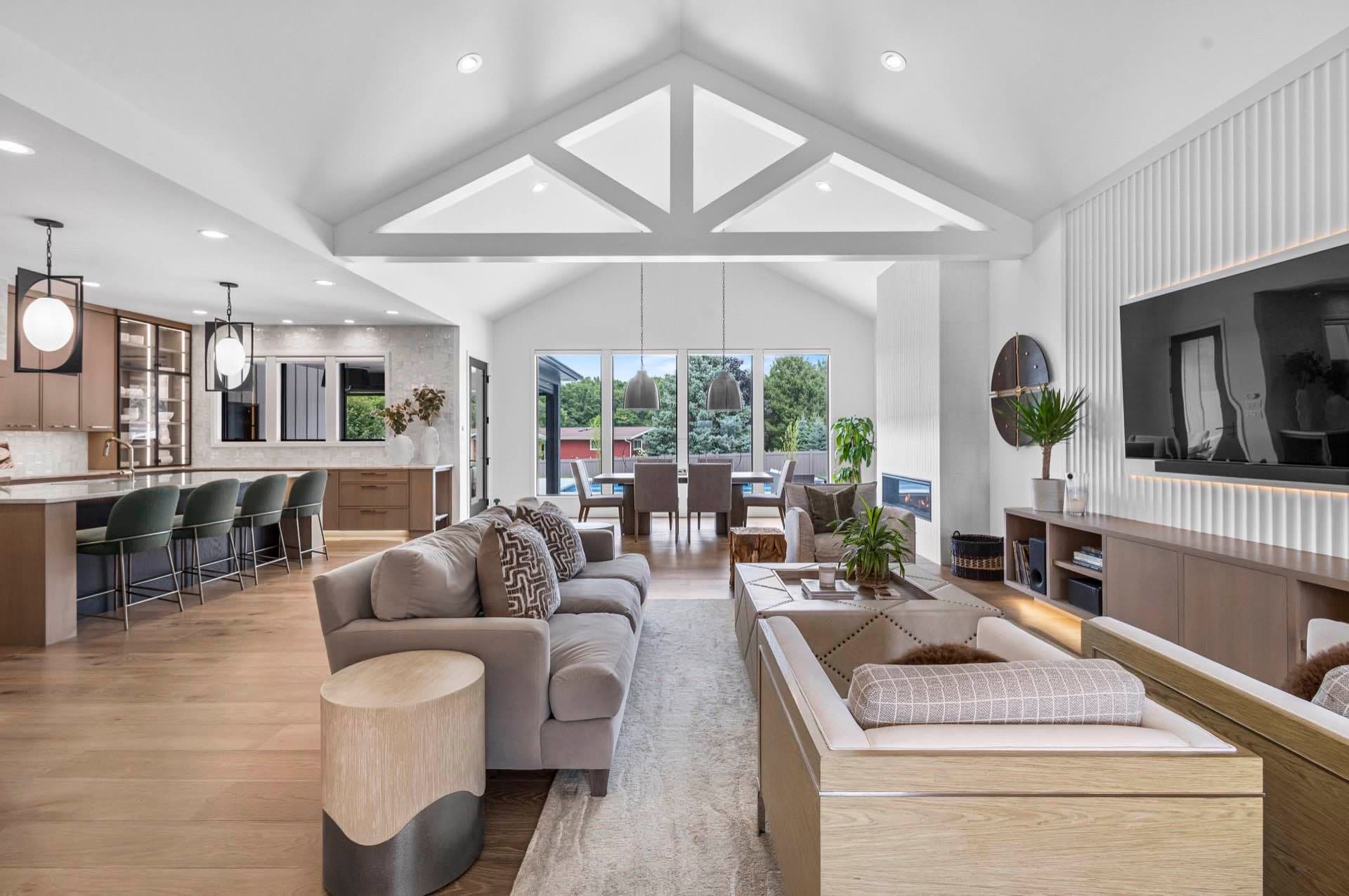 Open-concept great room under a vaulted ceiling with exposed white trusses