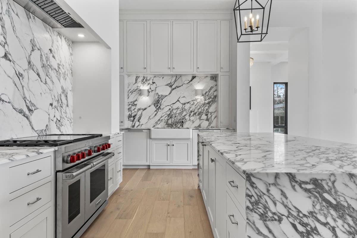 Chef kitchen with a book-matched marble backsplash and waterfall island