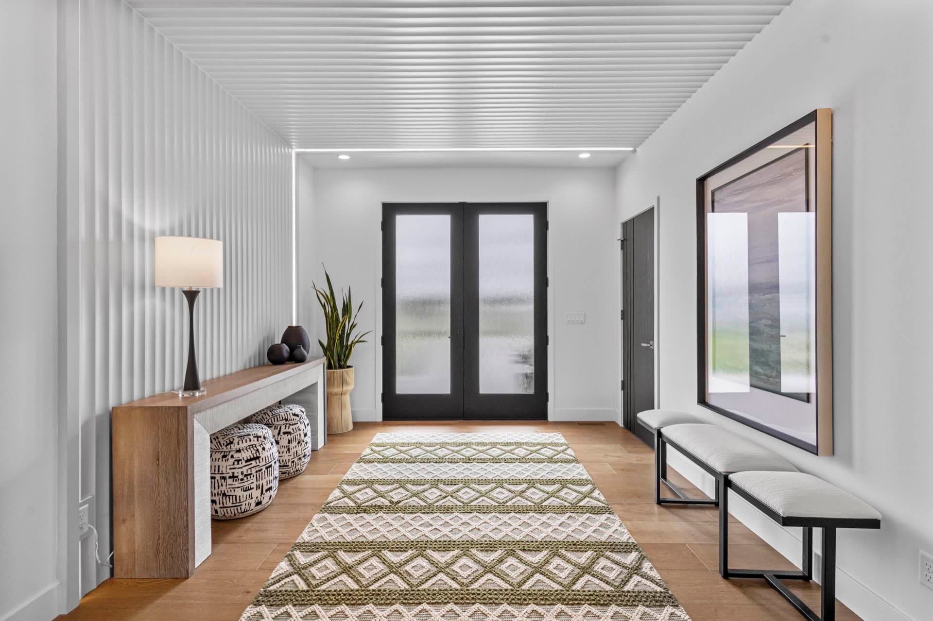 Entryway with a patterned runner leading to black double doors